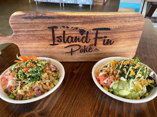 Two colorful Island Fin Poké bowls with branded cutting board at Beachwalk