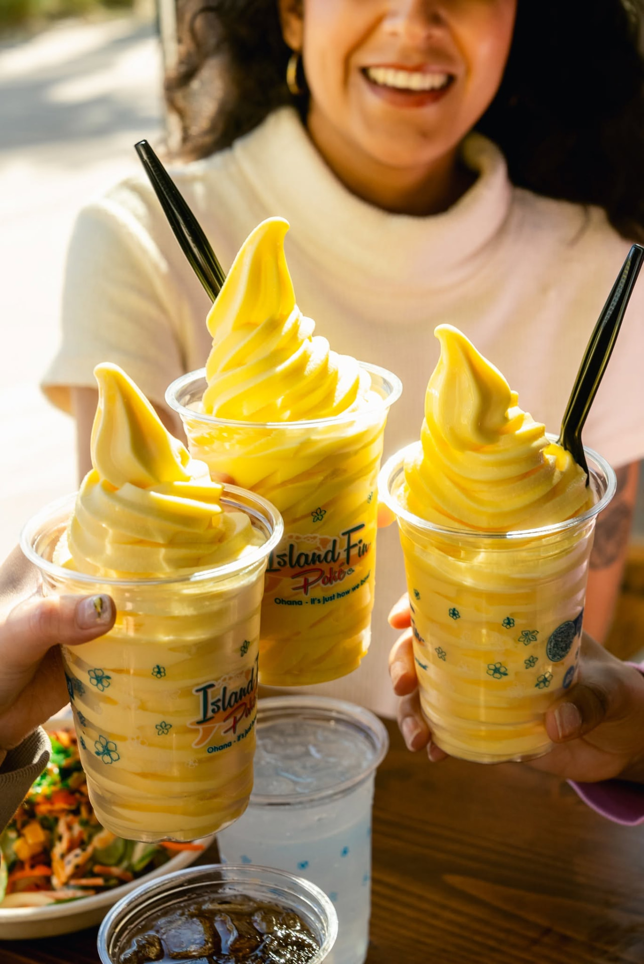Three Island Fin Poké DOLE Soft Serve® cups held up at the Beachwalk location