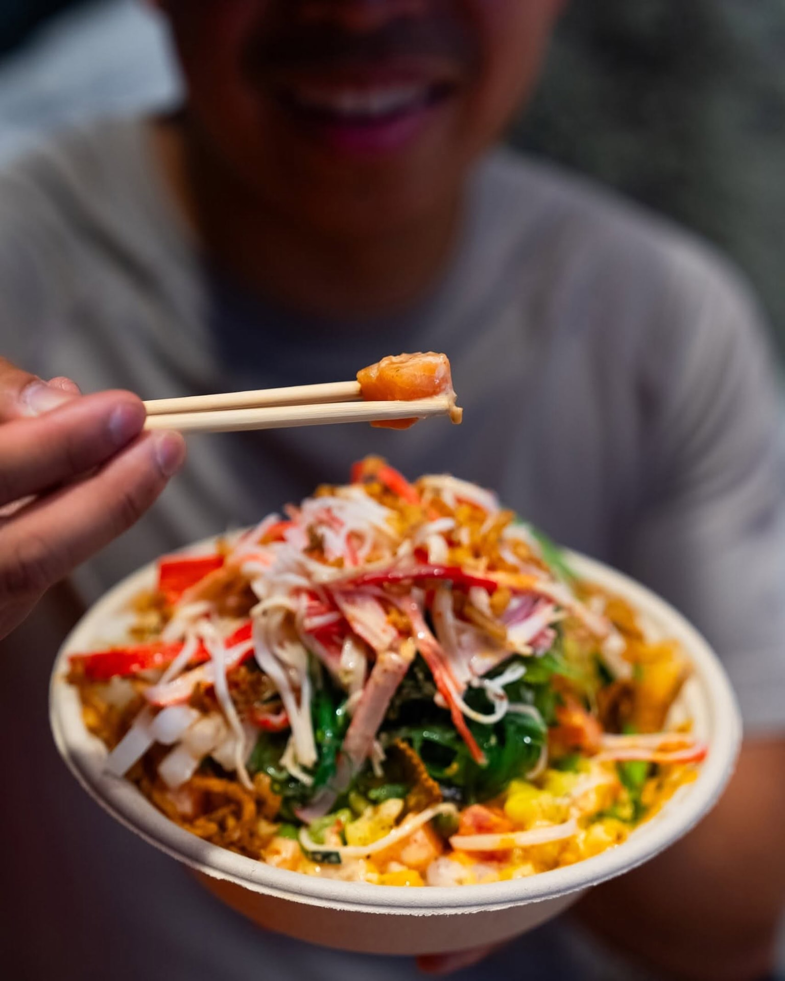 Fresh poké bowl held with chopsticks at Island Fin Poké Co. Beachwalk in St. Johns, Florida