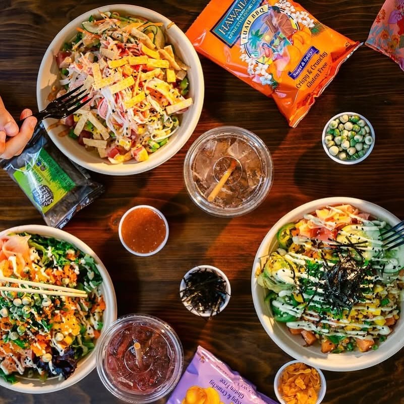 Overhead view of colorful finished poké bowls, drinks and toppings at Island Fin Poké Co. Beachwalk