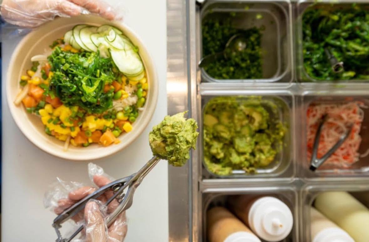 Fresh Island Fin Poké bowl being built with colorful toppings at Beachwalk